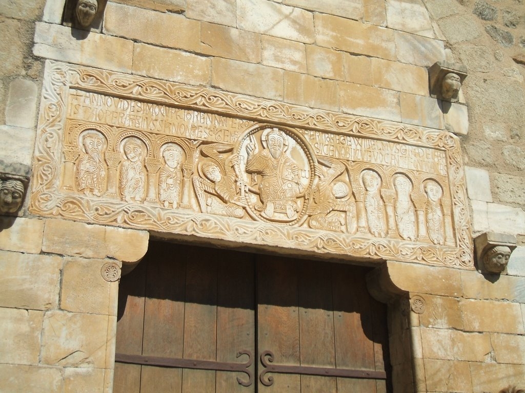 Façade extérieure de l'église Saint-Michel avec son portail, le linteau sculpté et les pierres qui le surmontent