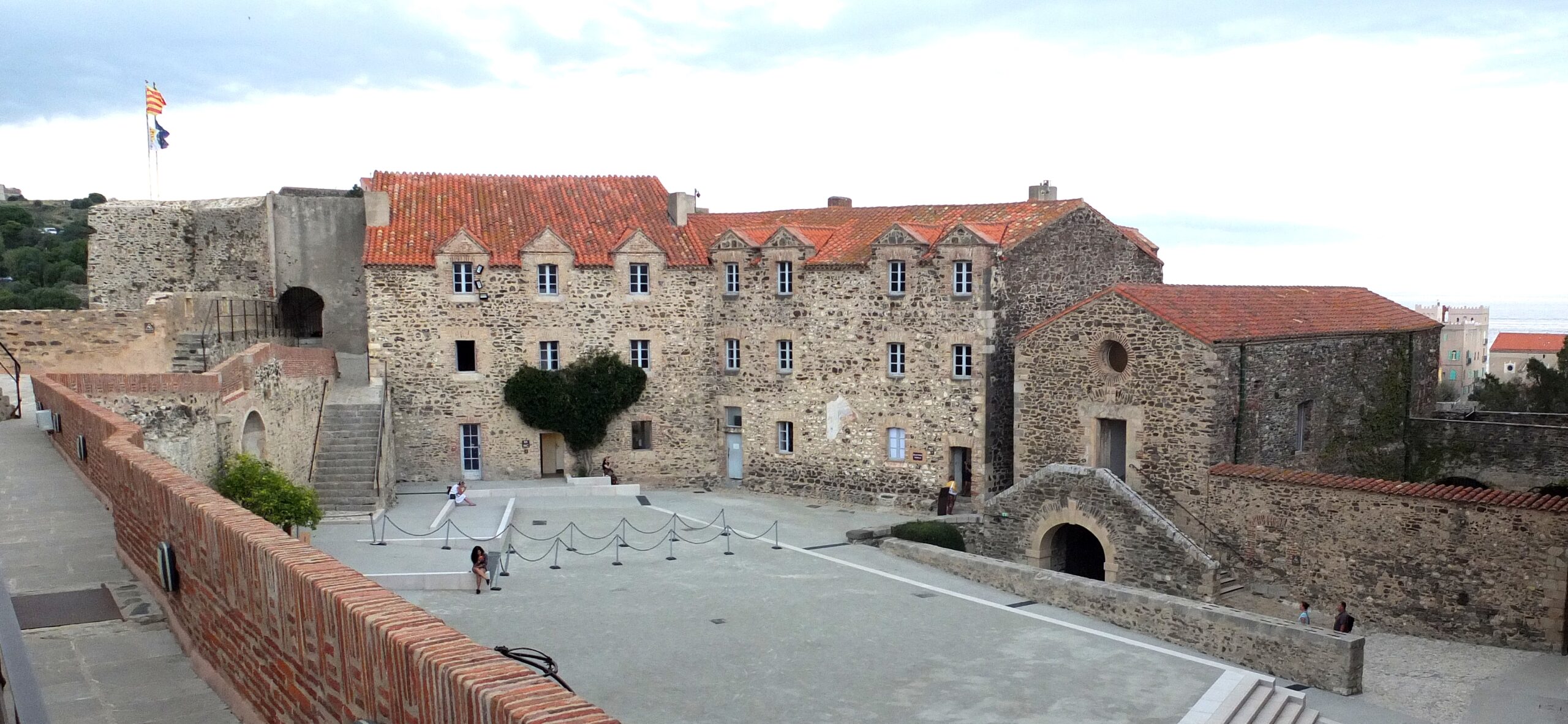 Cour intérieure du Château Royal de Collioure bordée de murs en pierre et d'anciens bâtiments militaires