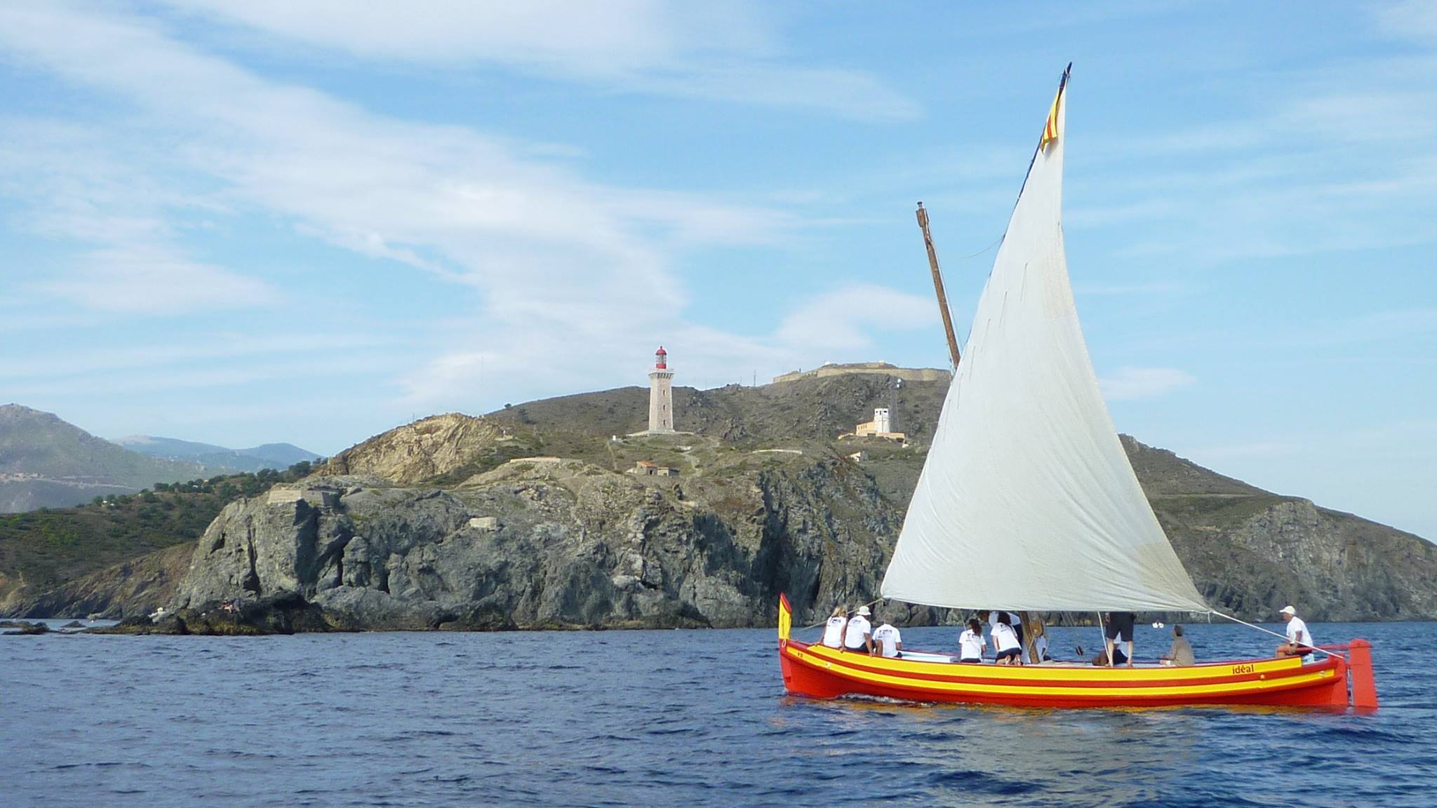 Une barque à voile latine devant le phare du cap Béar